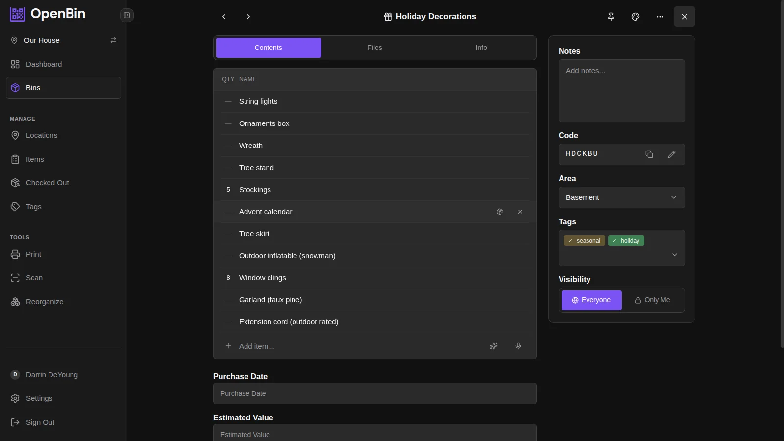 Christmas decoration storage bin detail showing string lights, ornaments, wreath, tree stand, and seasonal tags